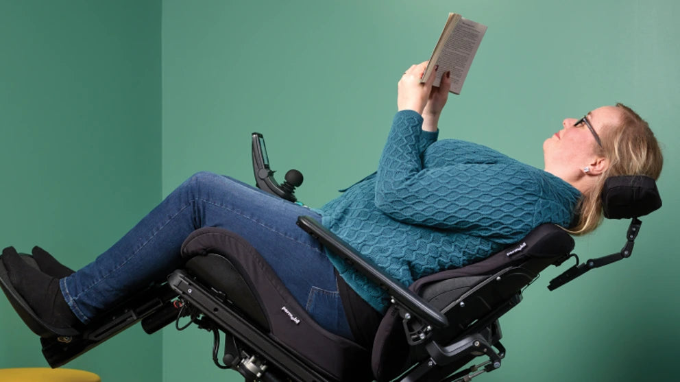 LADY READING A BOOK IN THE F3 CORPUS POWER CHAIR IN POWER RECLINE MODE